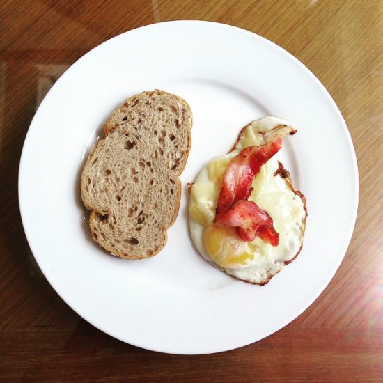 Grilled cheese on an egg with bacon and dark bread